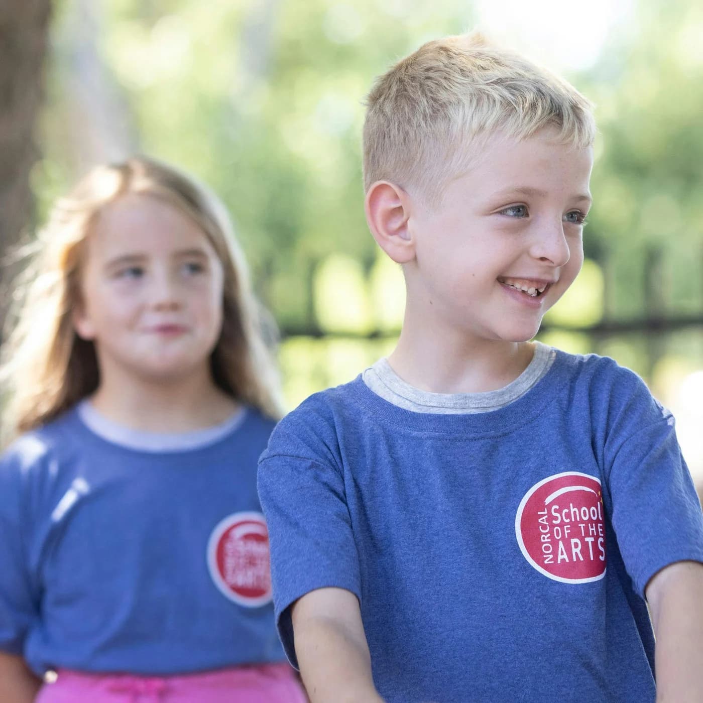 Young campers in blue NorCal Arts shirts outdoors